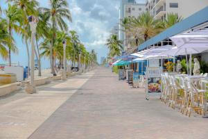 a beach with chairs and umbrellas and palm trees at CH Luxury Condos & Studios On The Beach in Hollywood