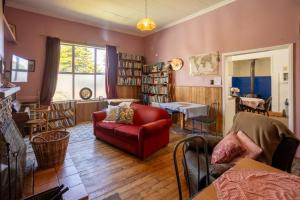 - un salon avec une chaise rouge et un canapé dans l'établissement Brunnerton Lodge and Backpackers, à Greymouth