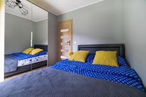 1 Schlafzimmer mit 2 Betten mit blauer Bettwäsche und gelben Kissen in der Unterkunft Agroturystyka Wena - luksus w naturze in Zachodźko
