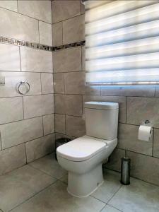 a bathroom with a white toilet and a window at Listos Guest House in Empangeni