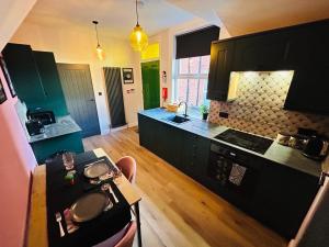 a kitchen with black cabinets and a wooden floor at Park Mount Residences - Boutique 1 Bedroom Apartment In Leeds With Free Parking in Kirkstall