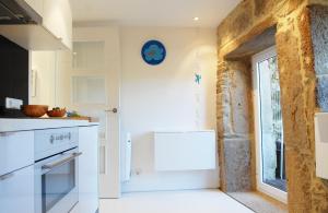 eine Küche mit weißen Geräten und einer Steinmauer in der Unterkunft Blue Home in Santiago de Compostela