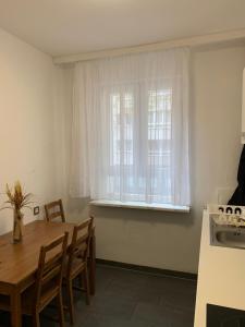 a kitchen with a table and a window with white curtains at Enjoy Berlin in Berlin