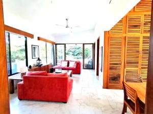 una sala de estar con 2 sofás rojos y ventanas en Ananda Guesthouse en Balgue