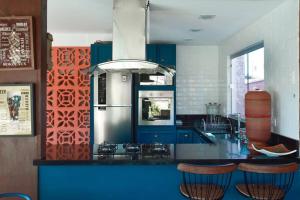 una cocina con armarios azules y una barra con taburetes en CASA SPA Pirenópolis casa inteira en Pirenópolis