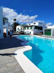 een vrouw die langs een zwembad loopt voor gebouwen bij Casa Turquesa, shared pool in Puerto del Carmen