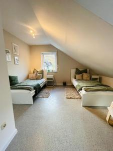 a attic room with two beds and a window at Stilvolles 4-Bett Appartment in Haiger