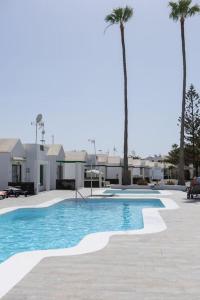 een zwembad met palmbomen voor een huis bij Casa Turquesa, shared pool in Puerto del Carmen +11 foto's