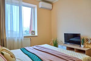 Schlafzimmer mit einem Bett, einem TV und einem Fenster in der Unterkunft Elite Lux Apartment with balcony in Mukatschewo
