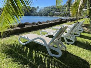 tres sillones blancos sentados en el césped cerca de un lago en NEW Luxury & Modern FARE MAOTI en Arue