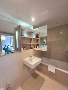 ein weißes Badezimmer mit einem Waschbecken und einem Spiegel in der Unterkunft 2-Bed Greenwich Flat + Pool, Gym, Lift, Balcony in London