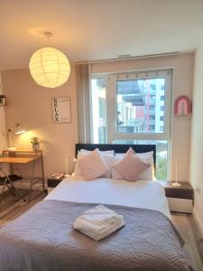 a bedroom with a large bed with a large window at 2-Bed Greenwich Flat + Pool, Gym, Lift, Balcony in London