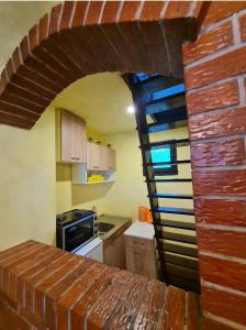a kitchen with a brick wall and a spiral staircase at Vikendica Alisa in Doboj