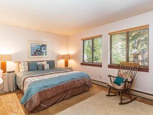 um quarto com uma cama, uma cadeira e janelas em A great mountain home offering amenities that makes for a great getaway in Lake Tahoe em Incline Village