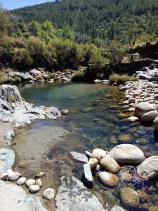 a river with rocks in the water and trees at Casa do Freire - Serra da Estrela in Aguincho
