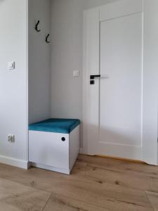 Habitación con armario blanco con banco azul en ApartTargowa, en Toruń