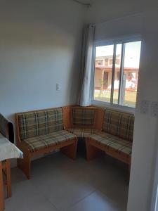 dois bancos sentados numa sala com uma janela em Condomínio Cordeiro em Arroio do Sal
