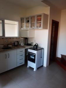 uma cozinha com armários brancos e um forno com placa de fogão em Condomínio Cordeiro em Arroio do Sal