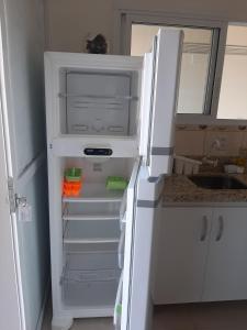 um frigorífico branco com a porta aberta numa cozinha em Condomínio Cordeiro em Arroio do Sal