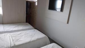 プレジデンテ・プルデンテにあるHOTEL ITAVERÁ BRASILのベッド2台と壁掛けテレビが備わる客室です。