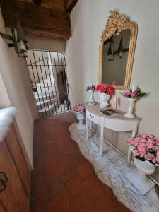 - un couloir avec un miroir et une table fleurie dans l'établissement La chatellenie Gîte de caractère de 1638., à Évaux-les-Bains