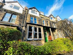 KirkstallにあるPark Mount Residences - Luxury 3 Bedroom Flat In Leeds With Free Parkingの白い窓と茂みのある古いレンガ造りの家