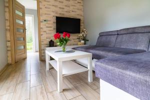 ein Wohnzimmer mit einem Sofa und einem Tisch mit Blumen in der Unterkunft Agroturystyka Wena - luksus w naturze in Zachodźko