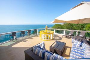eine Terrasse mit Stühlen, einem Sonnenschirm und dem Meer in der Unterkunft Del Playa Penthouse #6 Condo in West End