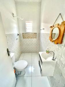 a white bathroom with a toilet and a sink at Pousada flor do sertão in Piranhas