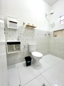 a white bathroom with a toilet and a microwave at Pousada flor do sertão in Piranhas