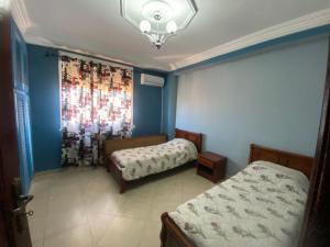 a bedroom with two beds and a window with a curtain at Appartement haut standing in Tlemcen