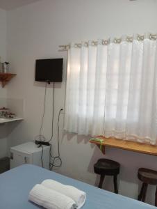 a bedroom with a bed and a window with white curtains at Pousada flor do sertão in Piranhas