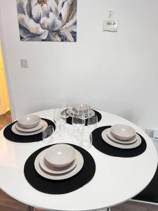 a white table with plates and wine glasses on it at Ava's Apartment - 1 Bedroom In Solihull Centre - Free Parking - Wi-Fi in Solihull