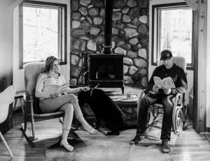 un homme et une femme assis sur des chaises devant une cheminée en pierre dans l'établissement Finnwood - A Pet Friendly Woodland Retreat, à Suttons Bay