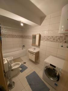 a bathroom with a toilet a sink and a washing machine at Violin 2 bedroom Apartment downtown Prizren in Prizren