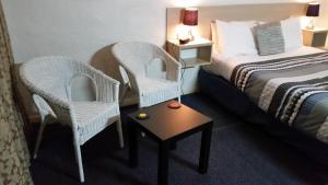 une chambre d'hôtel avec deux chaises, un lit et une table dans l'établissement Belmore Motor Inn, à Yarrawonga