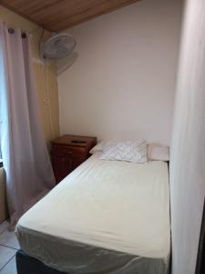 a small bedroom with a white bed and a window at La Casa de Cachi in Paquera