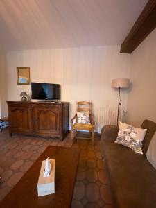 a living room with a couch and a tv at Gîte à la ferme in Viserny