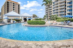 a swimming pool with chairs and umbrellas and buildings at Marco Beach Ocean Resort 1202 in Marco Island