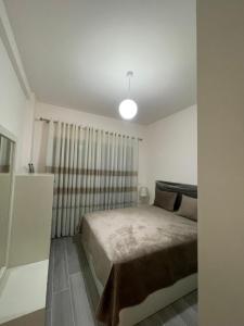 ein weißes Schlafzimmer mit einem Bett und einem Fenster in der Unterkunft Dreams Apartment in Korçë