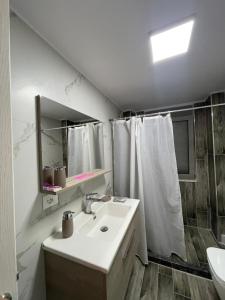 ein weißes Bad mit einem Waschbecken und einer Dusche in der Unterkunft Dreams Apartment in Korçë