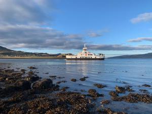 a large ferry boat in the water with mountains at Angusfield Cabins in Sconser