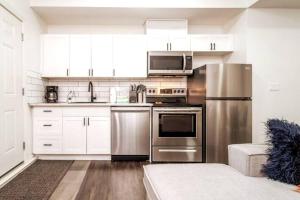 una cocina con electrodomésticos de acero inoxidable y armarios blancos en Chic Suite - Long Stays - King Bed - Fireplace & WiFi, en Edmonton