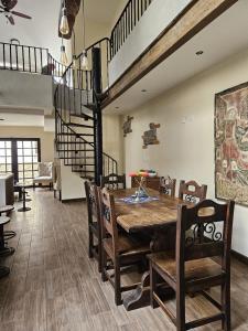 a dining room with a wooden table and a spiral staircase at Loft Candelaria Antigua in Antigua Guatemala