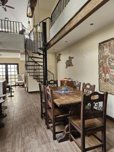 a dining room with a wooden table and a spiral staircase at Loft Candelaria Antigua in Antigua Guatemala +6 photos
