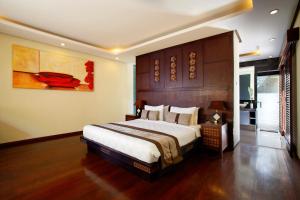 a bedroom with a large bed and a painting on the wall at Lalasa Villas Canggu in Canggu