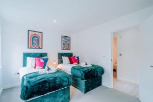 1 dormitorio con 2 camas con colchas verdes y taburete en Two Bedroom Urban Retreat in the Heart of Exeter en Exeter