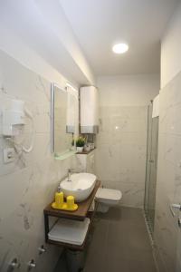 Un baño blanco con lavabo y ducha. en RomAntica Apartments, en Sarajevo