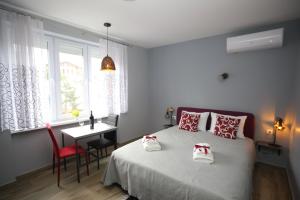 Un dormitorio con una cama y una mesa y una ventana. en RomAntica Apartments, en Sarajevo