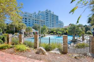 a fence in front of a pool with a large building at The Grand #2611 in Destin